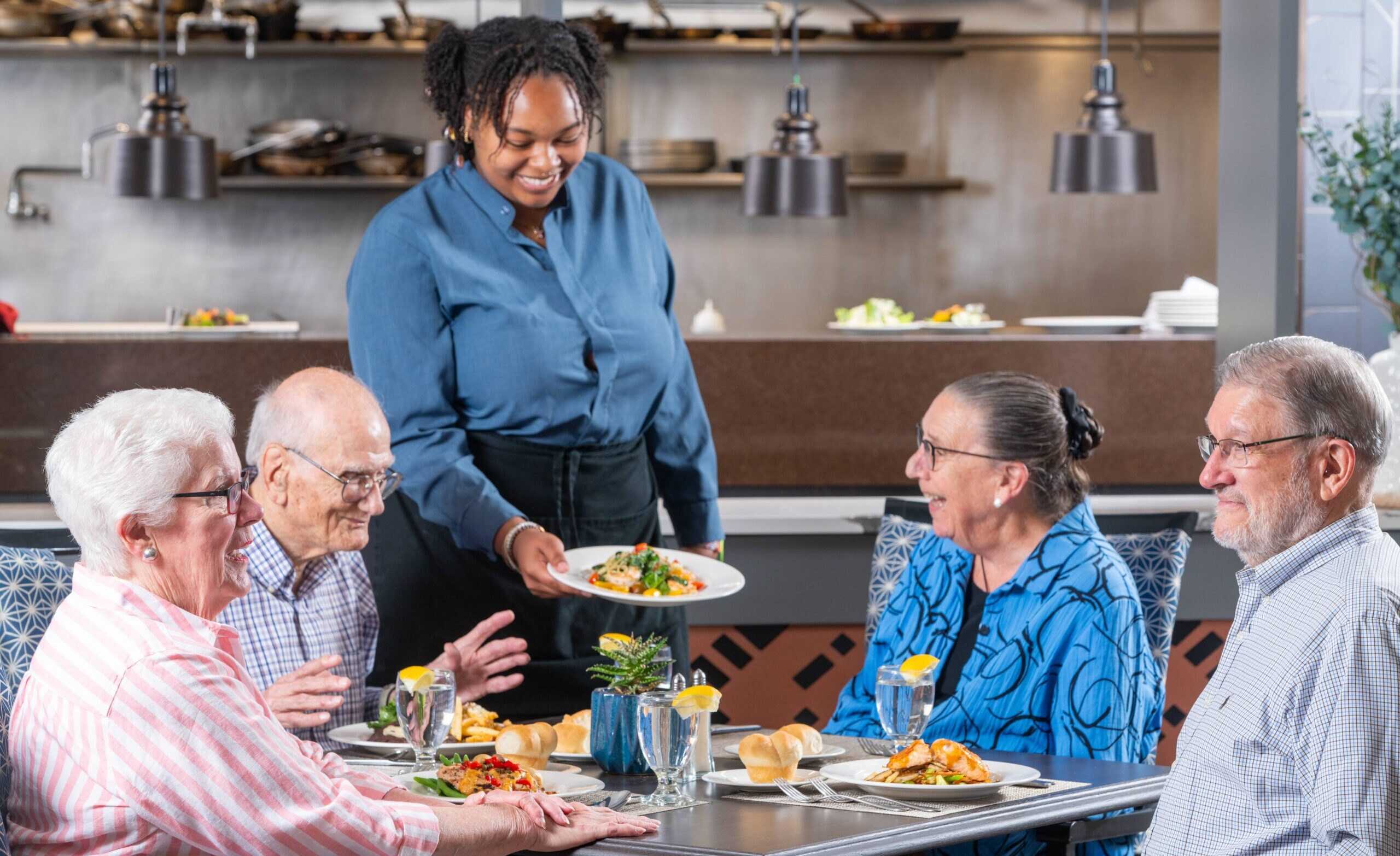 Residents having a meal in Promenade with server presenting a plate of food